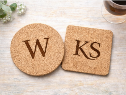 Two cork coasters with initials 'W' and 'KS' on a light wooden surface.