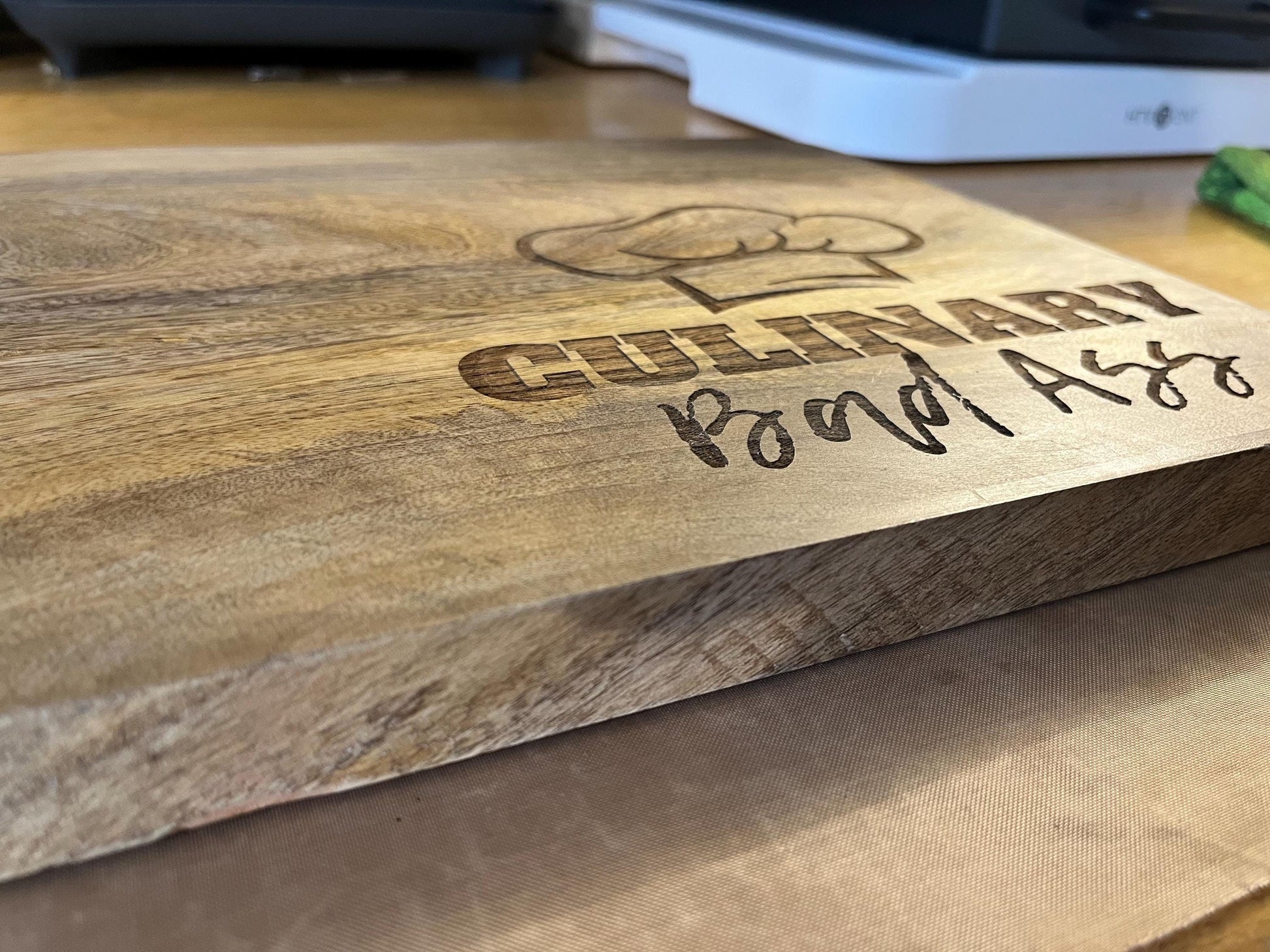 Wooden cutting board with 'Culinary Board Ass' engraving on a wooden surface.