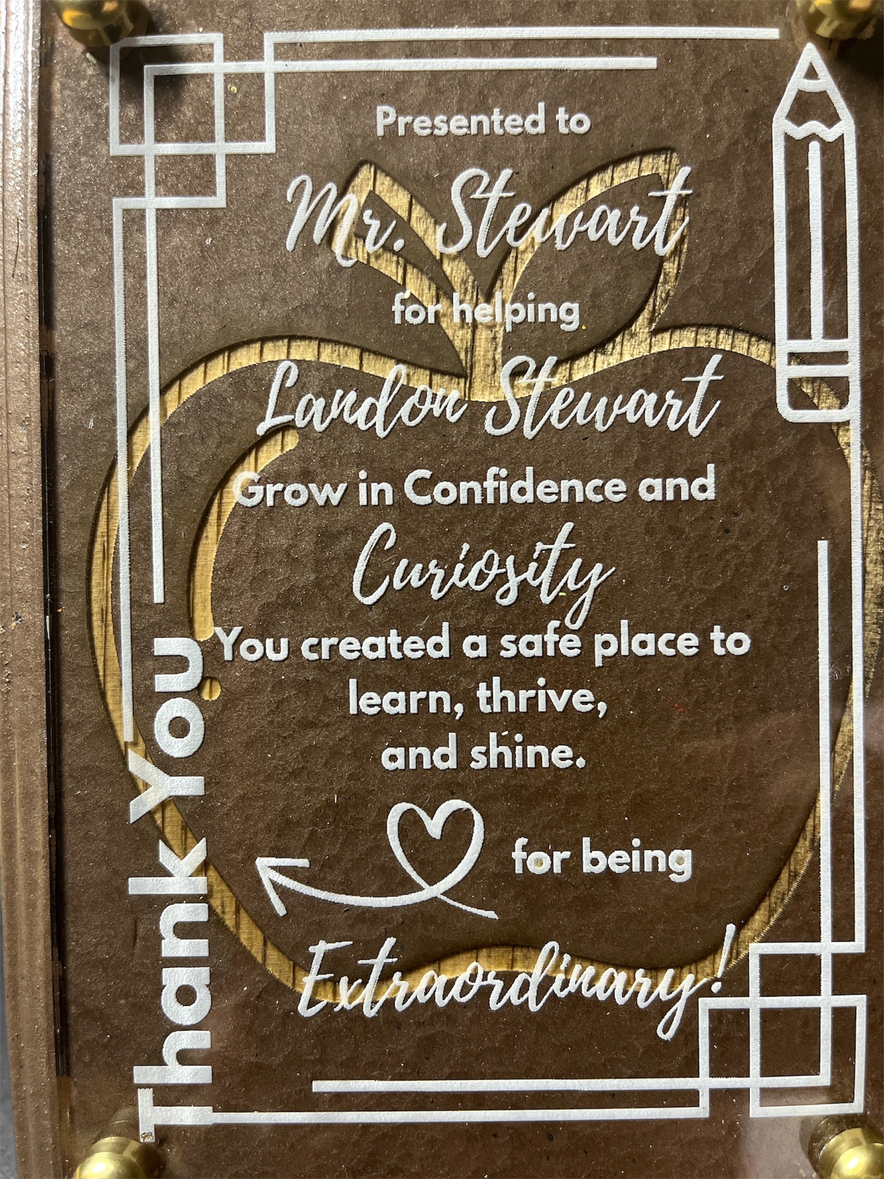 Decorative plaque with engraved text on a brown background
