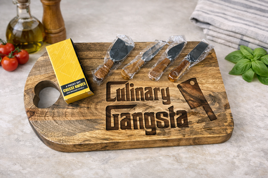 Wooden cutting board with 'Culinary Gangsta' engraving, cheese knives, and a block of cheese on a kitchen counter.