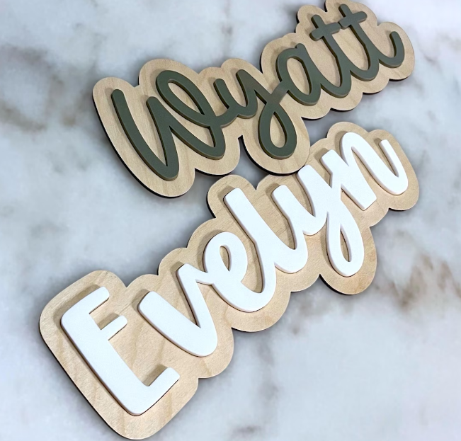 Wooden name plaques with 'Wyatt' and 'Evelyn' on a marble background